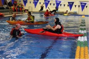 kayaker in the pool preparing to rool with a partner overseeing the process